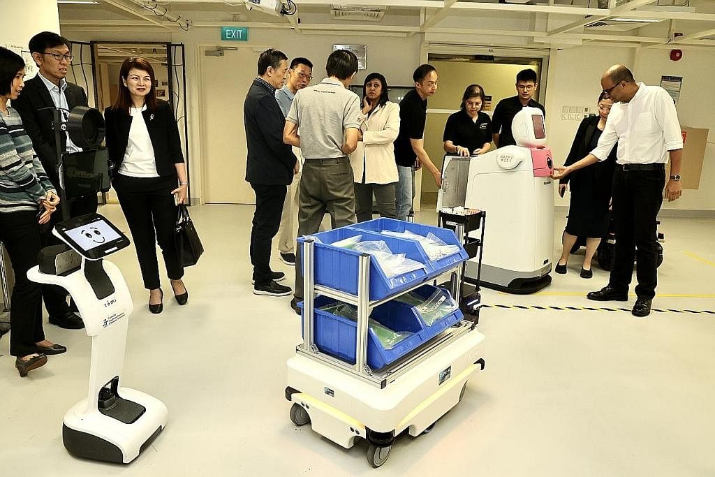  ​DEMONSTRASI SEPADU PENGGUNAAN ROBOT AUTONOMI Dr Janil Puthucheary (kanan) mengadakan kunjungan tertutup di Hospital Besar Changi untuk menyaksikan demonstrasi menyepadukan penggunaan robot autonomi melalui rangka kerja 'middleware', lapisan perisian yang membolehkan robot berbeza bercakap sesama sendiri. - Foto ZAOBAO 